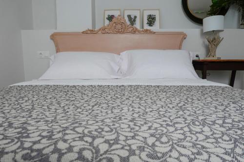 a bed with a white bedspread and a wooden headboard at Hospederia Santa Clara in Utrera