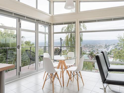 a dining room with a table and chairs and windows at Launceston Views Townhouses in Royal Park