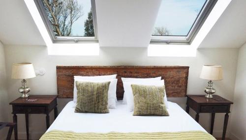 um quarto com uma cama com duas mesas de cabeceira e duas janelas em Eighteen21 Houses - Secluded Charm Cottage in Quinta Velha em Sintra