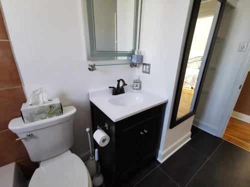 une salle de bain avec toilettes, lavabo et miroir dans l'établissement Appartement Maufils, à Québec
