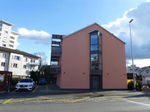 een roze gebouw met een auto geparkeerd op een parkeerplaats bij Plaza in Kreuzlingen