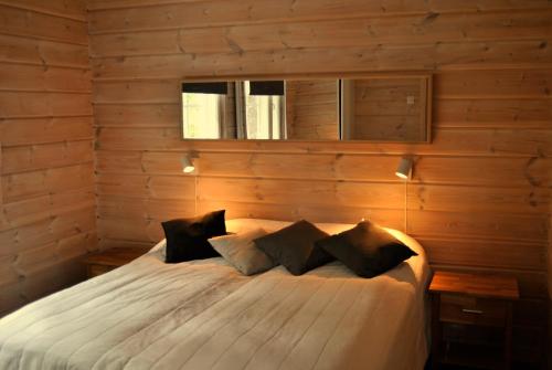 1 dormitorio con 1 cama con pared de madera en RukaNeliö Cottage, en Ruka
