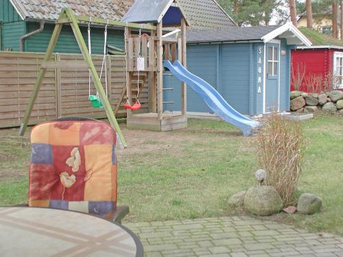 a yard with a playground with a slide at Ferienhaus Morgenstern F403 mit Kamin und Garten in Baabe