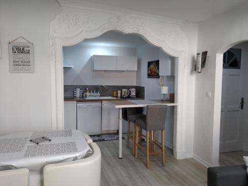 une cuisine blanche avec une table et un comptoir dans l'établissement FLOTS DE L ISLE, à LʼIsle-sur-la-Sorgue