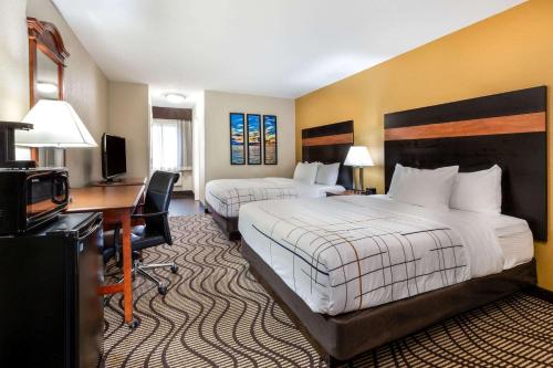 a hotel room with two beds and a desk at La Quinta Inn by Wyndham Sandusky near Cedar Point in Sandusky