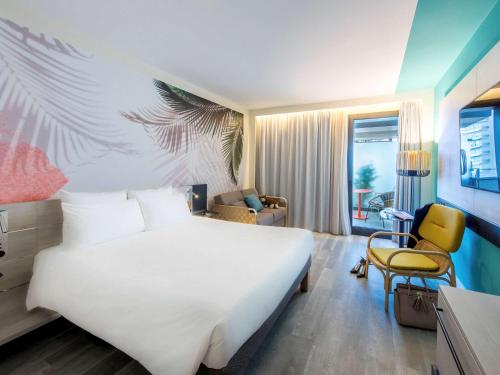 sypialnia z dużym białym łóżkiem i krzesłem w obiekcie Novotel Monte-Carlo w Monte Carlo