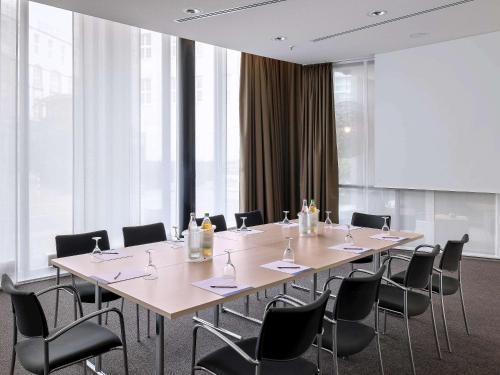 a conference room with a long table and chairs at Novotel Hannover in Hannover