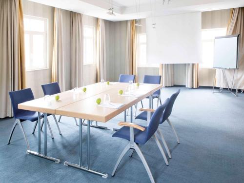 a conference room with a long table and chairs at Novotel Hildesheim in Hildesheim
