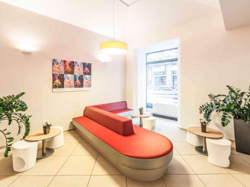 a waiting room with a red couch and two tables at Ibis Praha Old Town in Prague