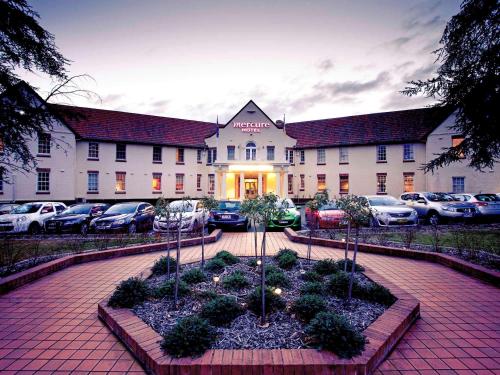 a building with cars parked in a parking lot at Mercure Canberra in Canberra