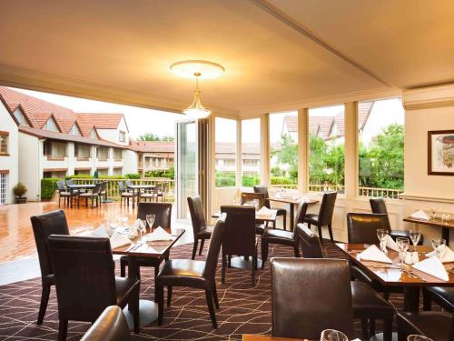 um restaurante com mesas, cadeiras e janelas em Mercure Canberra em Camberra