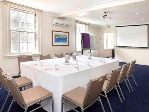 a conference room with a large white table and chairs at Mercure Canberra in Canberra