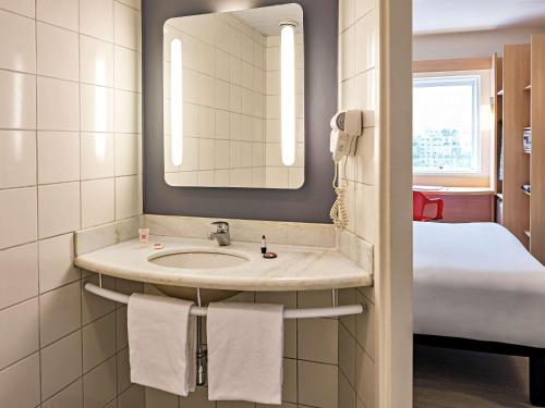uma casa de banho com um lavatório, um espelho e uma cama em ibis Rio de Janeiro Centro no Rio de Janeiro