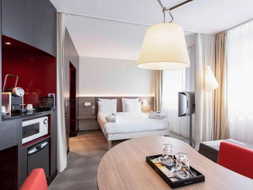 une chambre d'hôtel avec un lit et une table dans l'établissement Novotel Suites Genève Aéroport, à Genève
