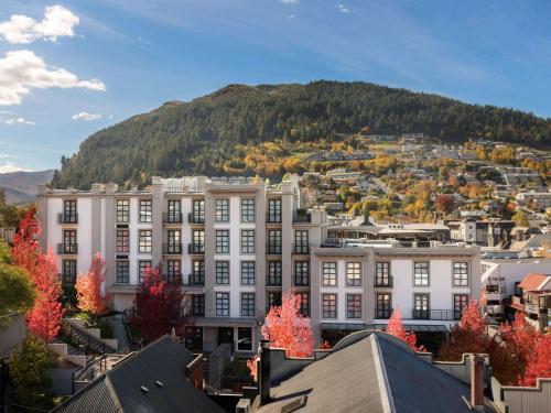 a large white building with a mountain in the background at Sofitel Queenstown Hotel & Spa in Queenstown