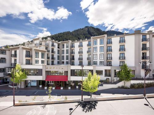 a large white building with a mountain in the background at Sofitel Queenstown Hotel & Spa in Queenstown