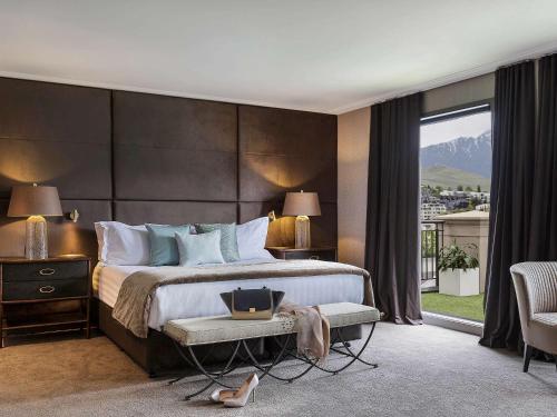 a bedroom with a large bed and a large window at Sofitel Queenstown Hotel & Spa in Queenstown