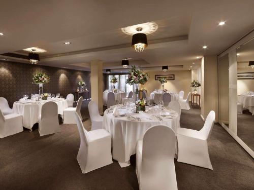 a banquet room with white tables and white chairs at Sofitel Queenstown Hotel & Spa in Queenstown