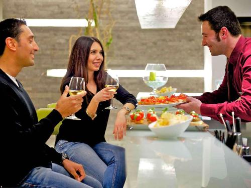 a group of people sitting around a table drinking wine at Mercure Palermo Centro in Palermo