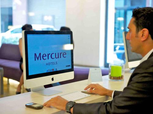 a man sitting at a desk working on a computer at Mercure Palermo Centro in Palermo