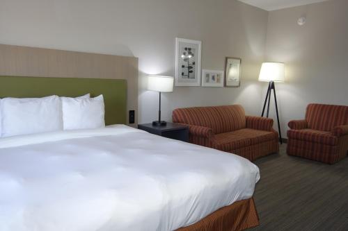 Country Inn & Suites by Radisson, Round Rock, TX في راوند روك: غرفه فندقيه بسرير كبير وكرسيين