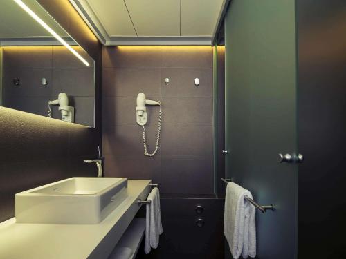 bagno con lavandino e telefono appeso al muro di Mercure Biel a Biel