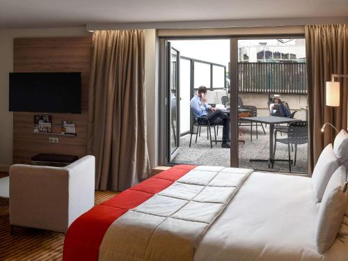 a hotel room with a large bed and a balcony at Mercure Paris Boulogne in Boulogne-Billancourt