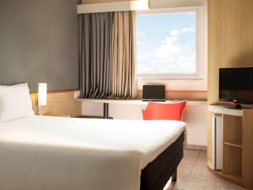 ein Hotelzimmer mit einem Bett und einem Fenster in der Unterkunft ibis Criciuma in Criciúma