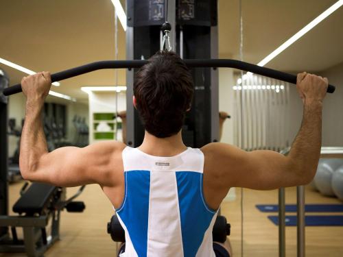 a man lifting a barbell in a gym at Pullman Sydney Olympic Park in Sydney