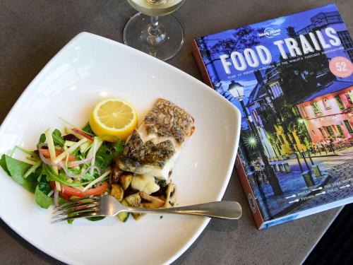 a plate of food with fish and a salad and a book at ibis Melbourne - Glen Waverley in Glen Waverley