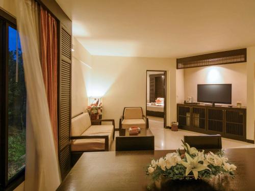 a living room with a couch and a television at The Nouveau Chumphon Beach Resort And Golf in Chumphon