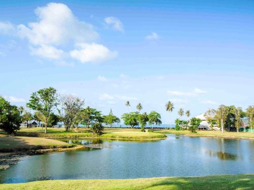a river in a park with palm trees and water at The Nouveau Chumphon Beach Resort And Golf in Chumphon