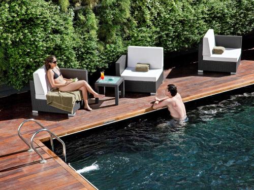 a man and woman sitting in the water in a pool at Novotel Buenos Aires in Buenos Aires