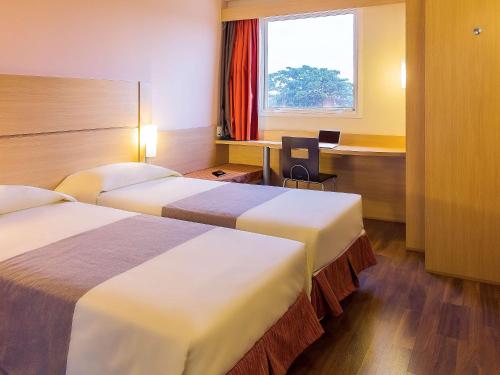 um quarto de hotel com duas camas e uma secretária em Ibis Mossoro em Mossoró
