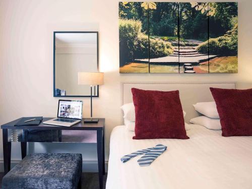 a bedroom with a bed with a desk and a mirror at Sunday Box Hill Burford Bridge Hotel in Dorking