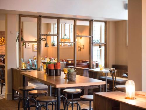 a restaurant with wooden tables and stools at Mercure Oxford Eastgate Hotel in Oxford