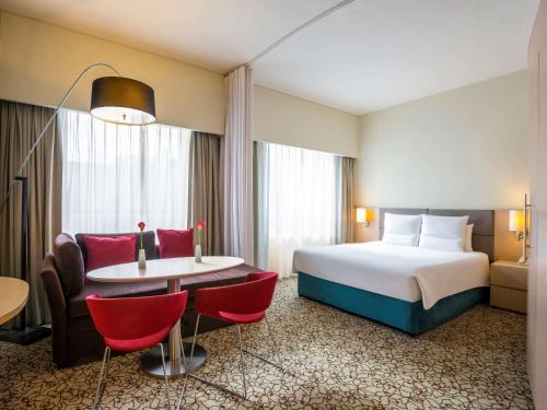 une chambre d'hôtel avec un lit, une table et des chaises dans l'établissement Novotel Suites Mall Avenue Dubai, à Dubaï