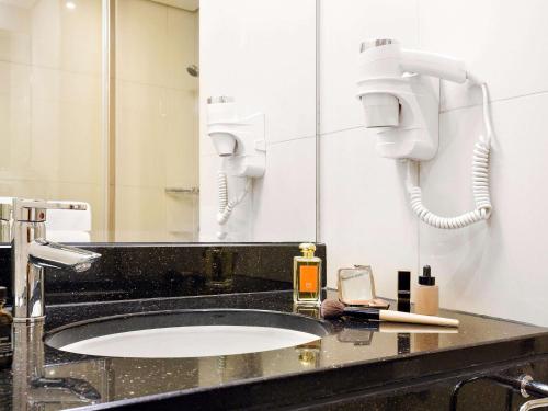 a bathroom with a sink with a mirror and a phone at Ibis Al Rigga in Dubai