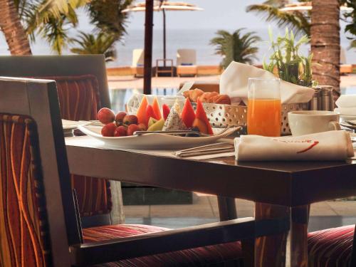 a table with a plate of fruit and a glass of orange juice at Novotel Mumbai Juhu Beach in Mumbai