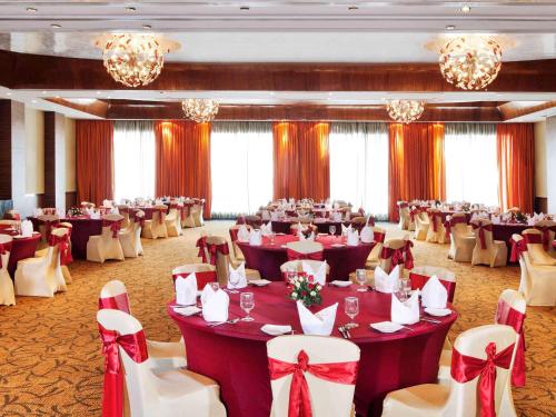 a banquet hall with tables and chairs and chandeliers at Novotel Mumbai Juhu Beach in Mumbai