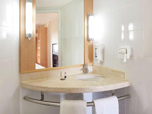 a bathroom with a sink with a mirror and towels at Ibis Merida in Mérida
