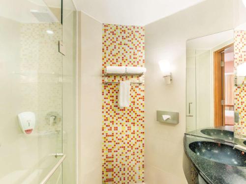 ein Bad mit einer Dusche und einem Waschbecken in der Unterkunft Hotel Ibis Semarang Simpang Lima in Semarang