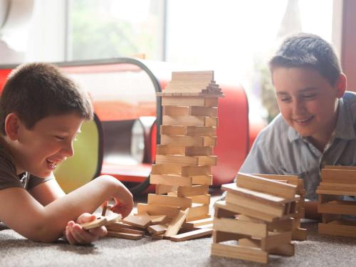 two boys playing with a wooden tower of bricks at Novotel Edinburgh Park in Edinburgh