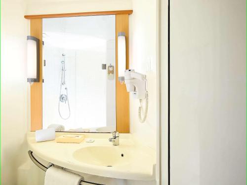 W łazience znajduje się umywalka i lustro. w obiekcie ibis Jaipur Civil Lines - An Accor Brand w mieście Dżajpur