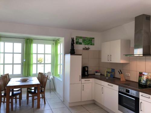 a kitchen with white cabinets and a table with chairs at Ferienhof Kolauerhof - Bauernhofurlaub in Grömitz in Grömitz