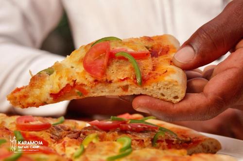 a person is holding a slice of pizza at Kara-Tunga Safari Camp in Moroto
