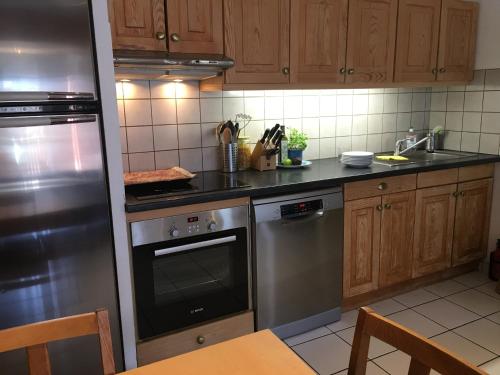 Central Morzine, Spacious 2 Bedroom Family Apartment في مورزين: مطبخ مع أجهزة ستانلس ستيل ودواليب خشبية