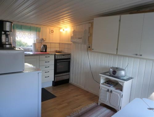 a small kitchen with white cabinets and a stove at Karlholm Snatra Stugområde in Karlholmsbruk