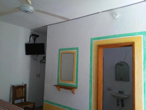 a bathroom with a mirror and a sink on a wall at Hotel Sarabi in Barra de Navidad
