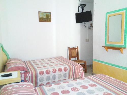 a bedroom with two beds and a tv in it at Hotel Sarabi in Barra de Navidad